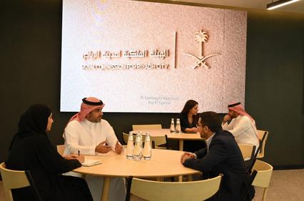 A group of people engaged in a discussion at a table in a modern office setting.