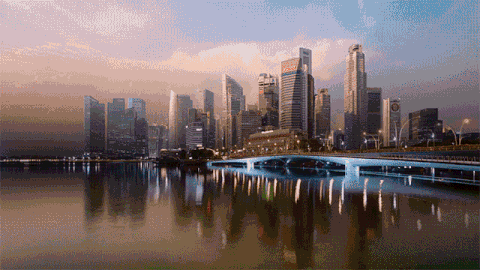 A beautiful skyline of a modern city reflected in the water during sunset.