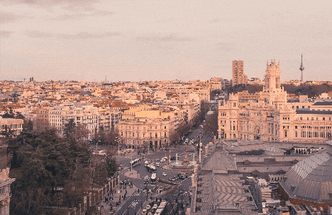 A panoramic view of a cityscape during sunset with various buildings and streets.