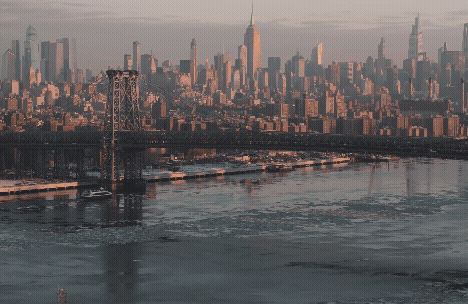 A scenic view of a city skyline at dusk with a bridge in the foreground.