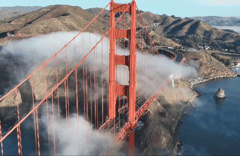A view of the Golden Gate Bridge surrounded by fog and hills.