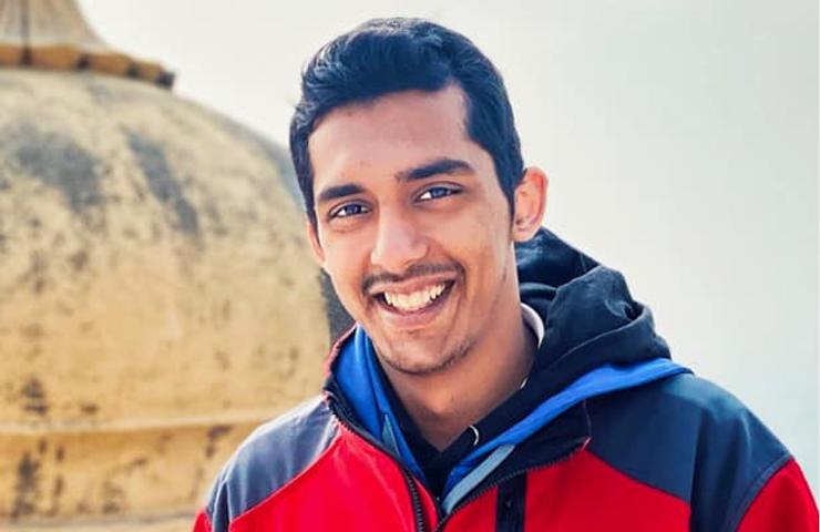 Anurag Phalke, design and architecture student, smiles at the camera with a building in the back