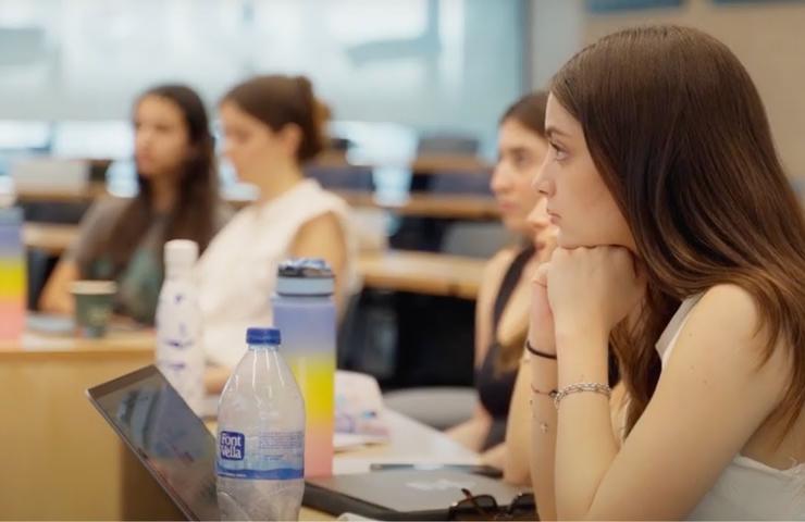 Young women sitting and focusing intently in a classroom setting with laptops open.