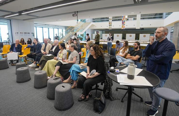 A group of people sitting and listening to a speaker in a modern office seminar room.