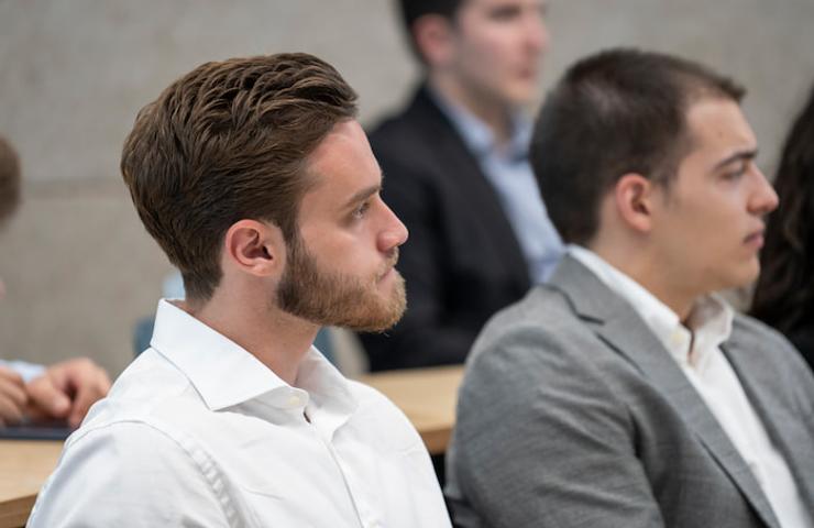 Two men, one with a beard and the other clean-shaven, attentively participating in a lecture or meeting.