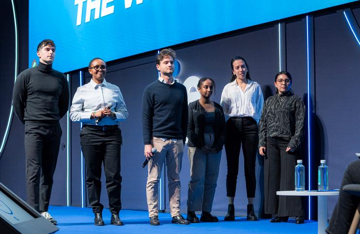 A group of young professionals standing together on stage during a presentation.