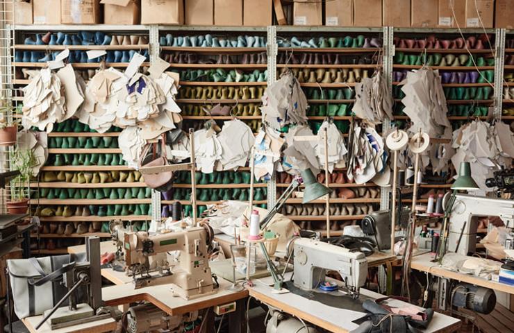 A busy tailoring workshop with sewing machines, fabric rolls, and partially assembled garments.