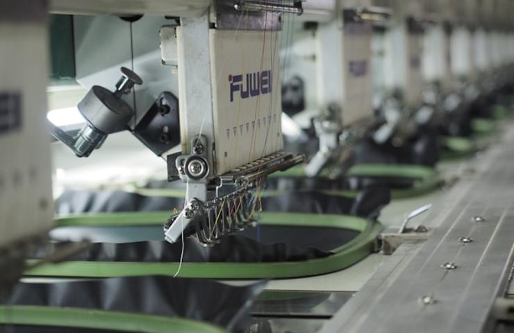 This image shows a row of embroidery machines in a textile manufacturing setting.