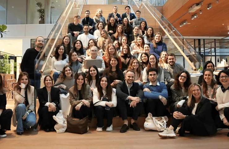 A large group of people posing for a photo on steps inside a modern building.