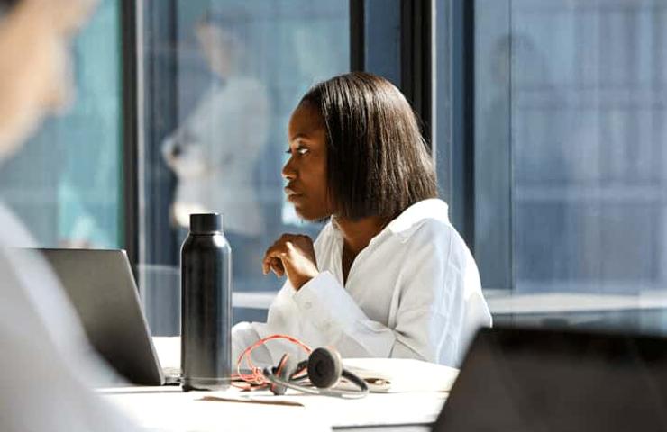 A focused woman working on a laptop in a modern office setting.