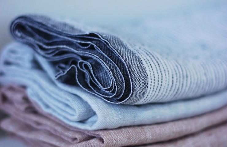 A stack of neatly folded linen fabrics in various muted colors.