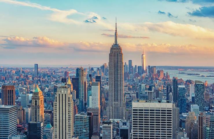 A panoramic view of New York City skyline at sunset, featuring the Empire State Building.