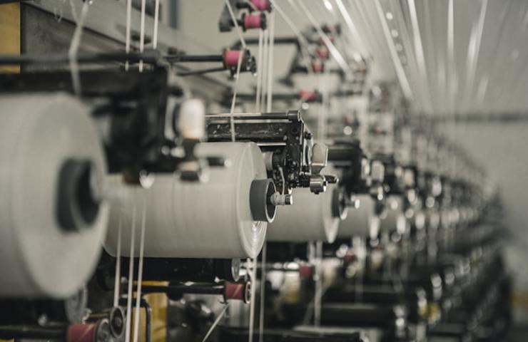 An image showing a row of textile machines spinning yarn in an industrial setting.