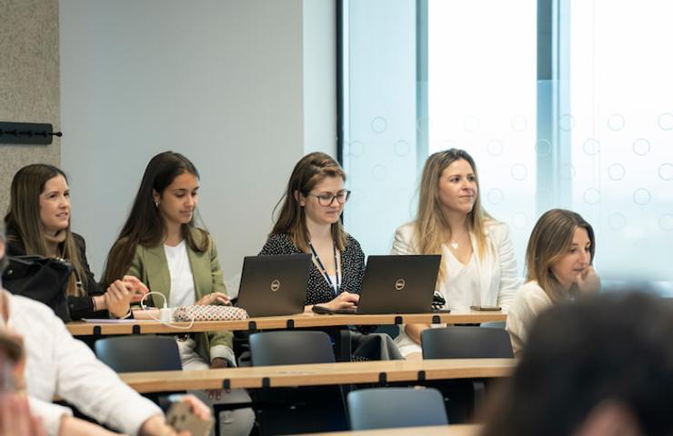 A group of women attentively using laptops in a classroom setting.