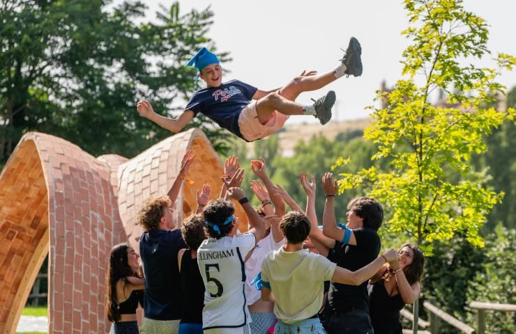 A young man performs a flip being tossed by a group of friends in a park