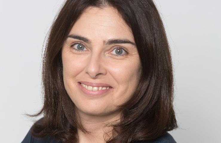 Portrait of a smiling woman with shoulder-length dark hair wearing a dark blue top.