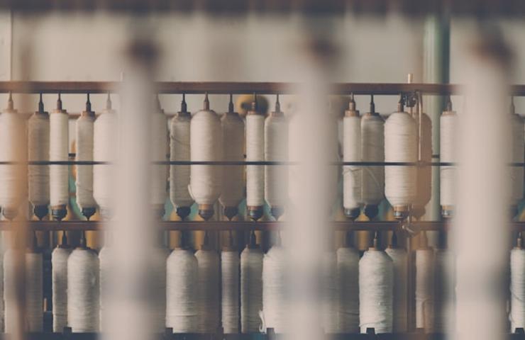 A blurred view of spools of thread on racks in a textile manufacturing setting.