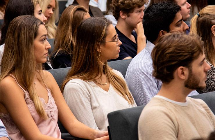 A group of young adults attentively listening in a seminar or classroom setting.