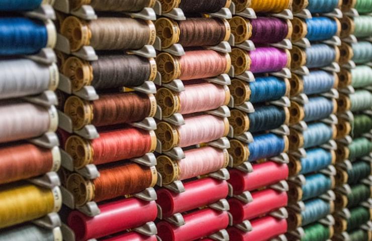 A colorful display of numerous spools of thread organized neatly on shelves.