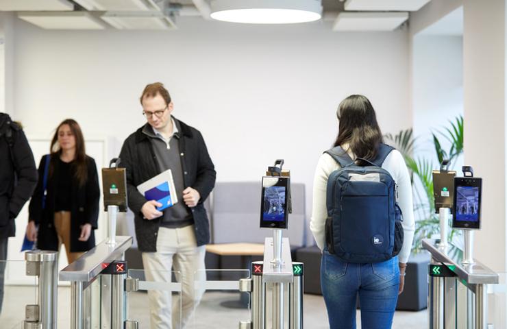 People entering an office through modern electronic access gates.