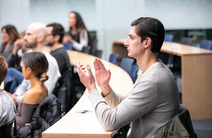 A young man raises his hands in engagement during a classroom discussion.