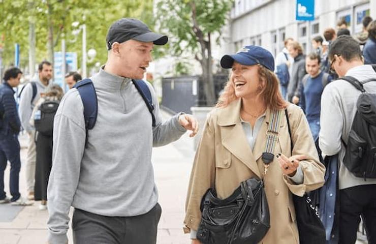 A young man and woman in casual clothes talking and laughing while walking on a busy street.