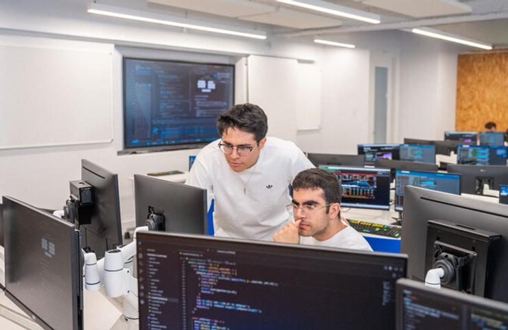 Two students are collaborating on programming tasks in a computer lab.