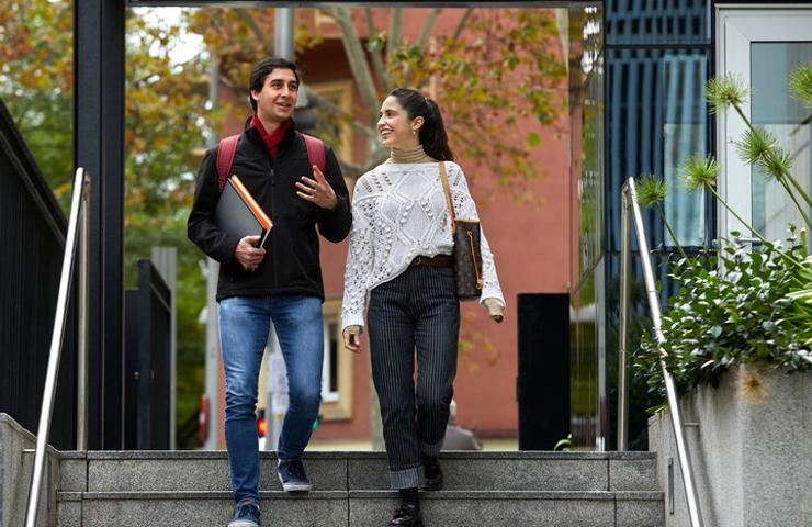 Two students walking down stairs while engaging in a conversation