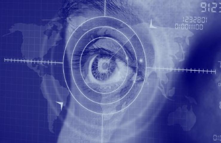 An eye overlaid with digital interfaces on a blue map background, symbolizing modern surveillance or data analysis.