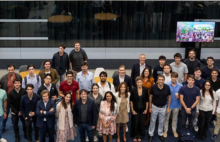 A group of people standing together in a modern indoor space with a presentation screen in the background.