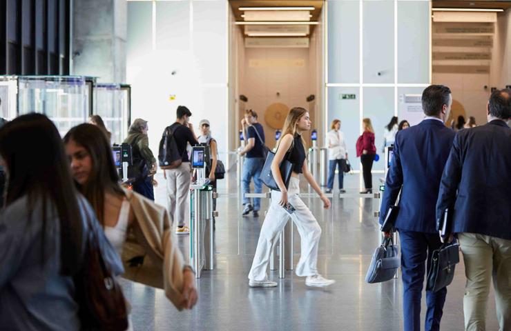 A busy airport terminal with travelers passing through security gates.