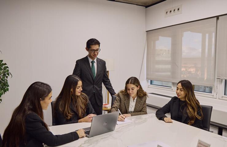 A group of young professionals engaged in a meeting around a conference table.