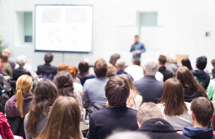 A crowd of people attending a presentation in a lecture hall.