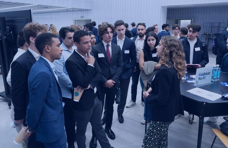 A group of young professionals listening to a speaker at a networking event.