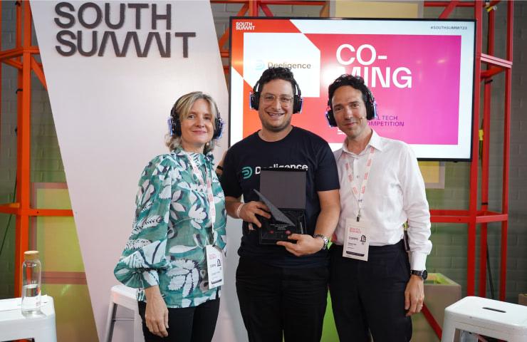 Three people posing together at a tech event, with one of them holding an award.