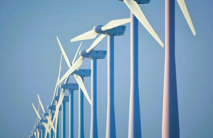 A row of wind turbines against a clear blue sky.