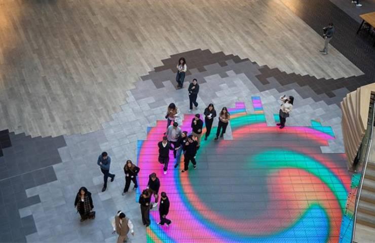 A group of people standing on a colorful interactive floor display in a spacious room.