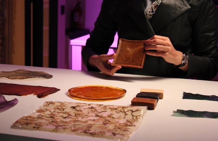 A person is showing a textured object while various materials are displayed on the table.