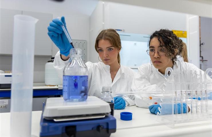 Two women in lab coats are conducting an experiment in a laboratory.