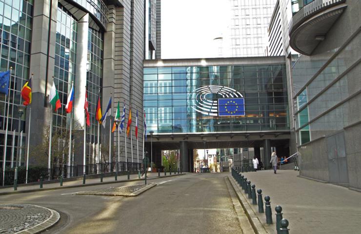 A view of the European Parliament building in Brussels with various flags displayed.