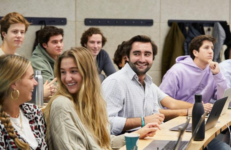 A group of students engaged in a classroom setting, some smiling and interacting.