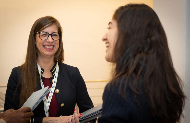 Two women are having a joyful conversation at an event.