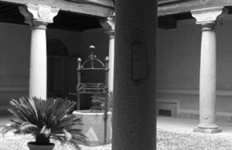 Black and white photo of a serene courtyard with classical columns and a central water well.