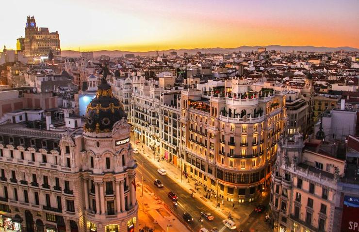A panoramic view of a cityscape at sunset, showcasing vibrant buildings and a golden sky.