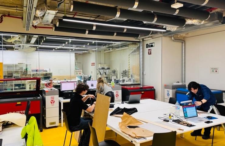 A busy workspace featuring multiple individuals working with computers and laser cutting machines.