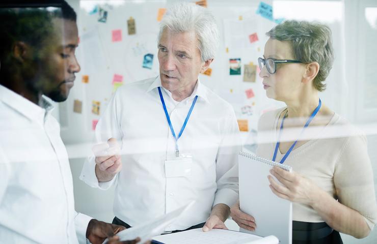A team of three professionals discussing ideas in an office setting.