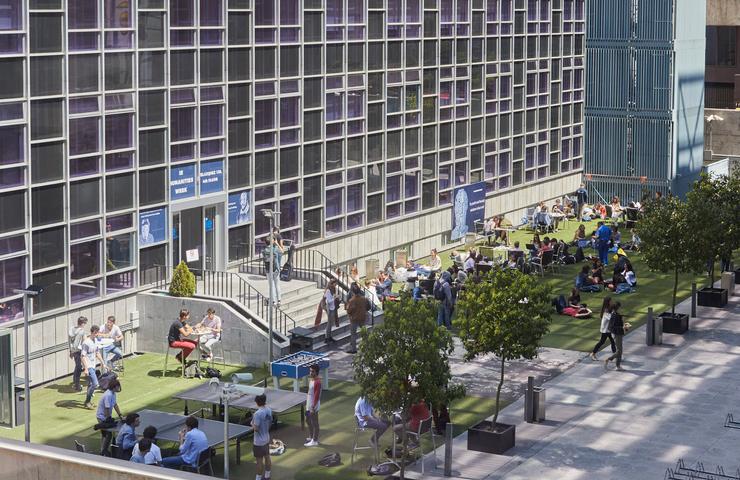 People socializing in a modern urban park with building facades in the background.