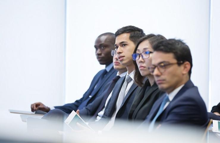 A group of diverse professionals attentively listening during a meeting.