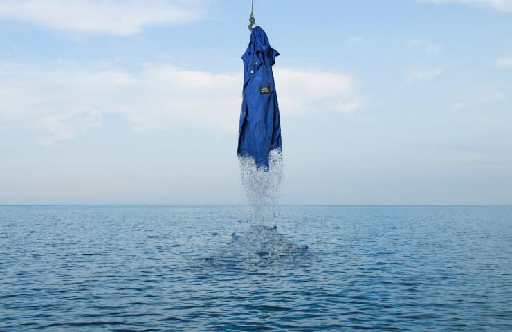 An umbrella hanging and dripping water above a calm sea.