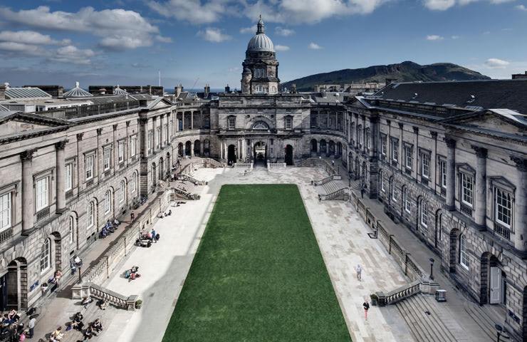 A view of a grand classical building with an open courtyard, under a clear sky.